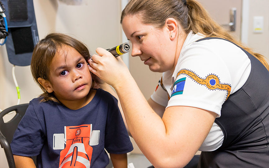 A young boy and an adult clinician using a device to do a hearing test