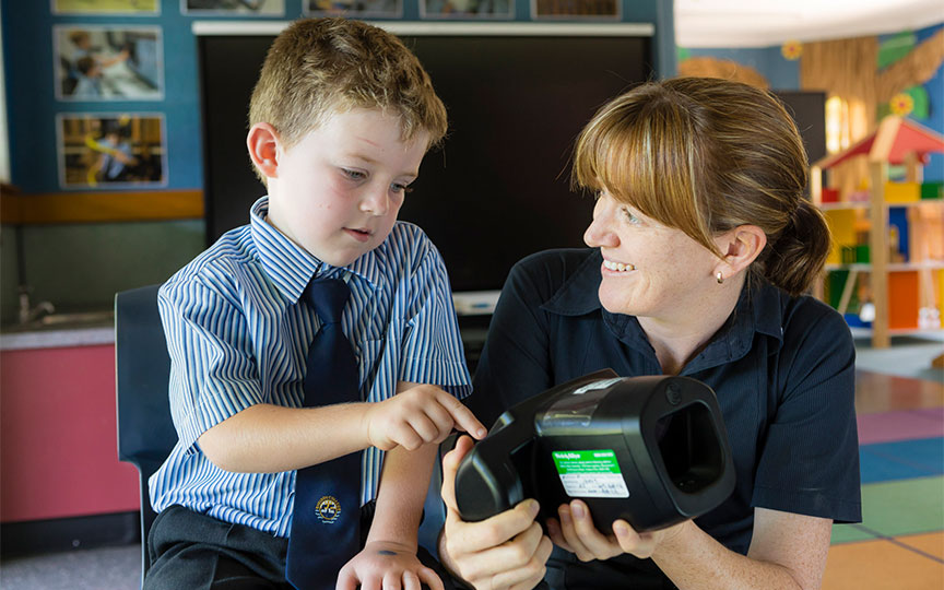 A young boy and an adult clinician looking at a device to do a vision test