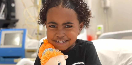 Young girl smiling holding a doll