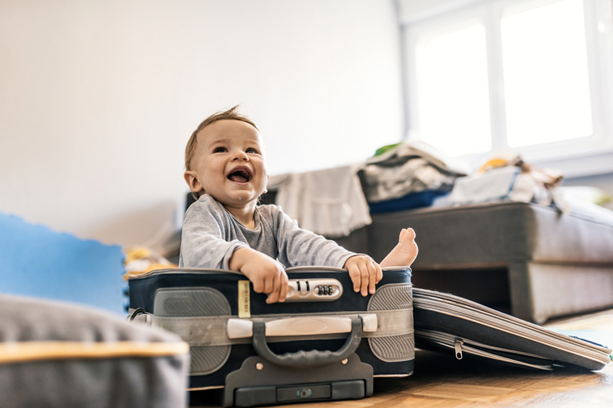 Laughing toddler sitting in an open suitcase