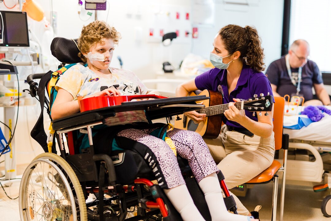 Smiling girl with ukulele having a music therapy session.